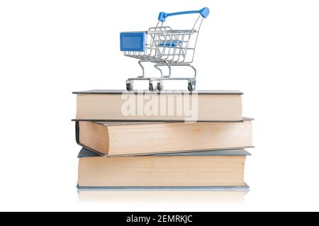 Shopping cart on top of a pile of books with reflection on white background Stock Photo