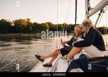 Happy senior couple using mobile phone during sunset Stock Photo