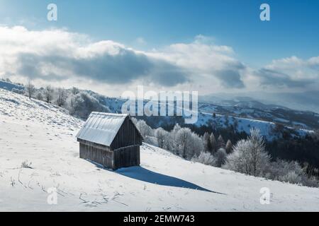 Fantastic winter landscape with wooden cabin in snowy forest. Cozy house in Carpathian mountains. Christmas holiday concept