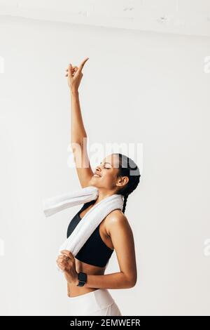 Happy fit woman with closed eyes raise hand up and pointing with a finger Stock Photo