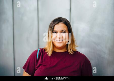 Portrait of smiling female student against gray wall Stock Photo