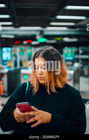 Female student using smart phone at subway during night Stock Photo