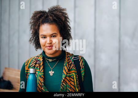 Smiling female student against gray wall Stock Photo