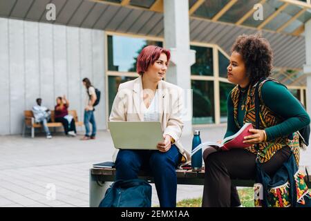 Female students talking with each other while studying in university campus Stock Photo