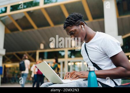Male college student studying online on laptop in university campus Stock Photo