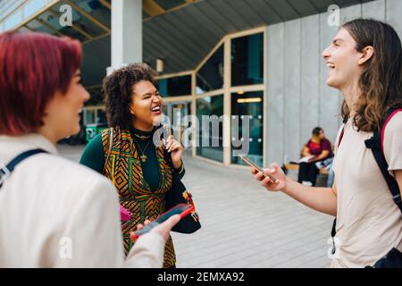 Young university students laughing while talking with each other at college campus Stock Photo