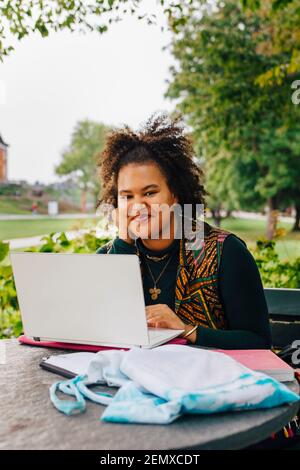 Smiling female student with laptop in college campus Stock Photo
