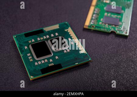 Computer processor, RAM and other accessories on the table. Spare parts for a mobile computer. Dark background. Stock Photo