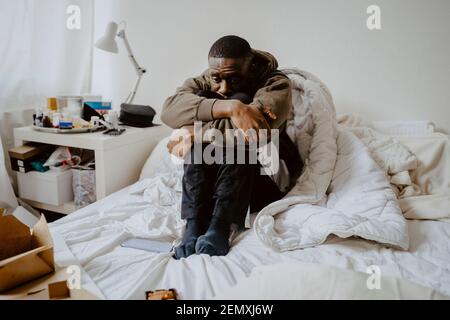Depressed man sitting on bed at home Stock Photo