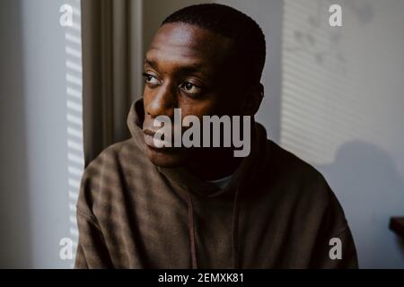 Thoughtful man looking away against wall Stock Photo