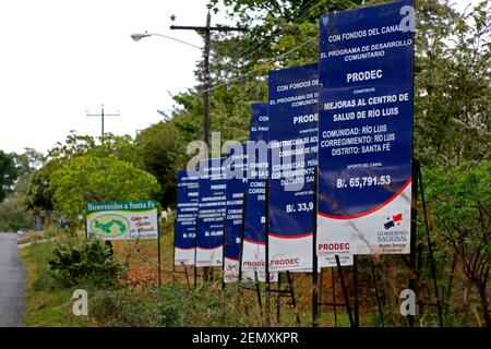 Sign promoting improvements to Rio Luis community health centre funded by payments from the Panama Canal, Santa Fe, Veraguas Province, Panama Stock Photo