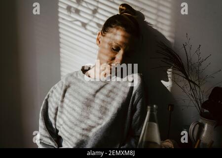 Mature woman with eyes closed against wall at home Stock Photo