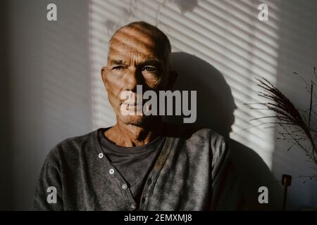 Thoughtful senior man against wall at home Stock Photo