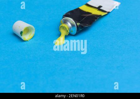 Tube of spilling yellow acrylic paint on art paper background Stock Photo