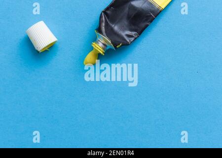 Tube of spilling yellow acrylic paint on art paper background Stock Photo