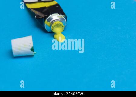 Tube of spilling yellow acrylic paint on art paper background Stock Photo