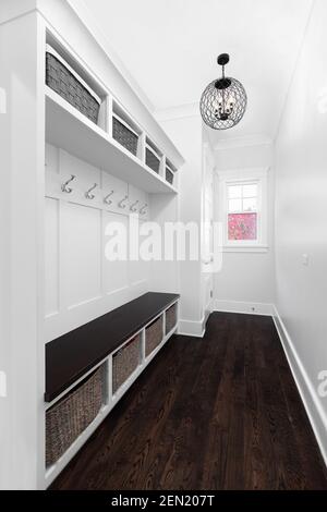 A luxurious mud room with built-in bench seating, coat hooks, and bins in small cubes for storage. Stock Photo