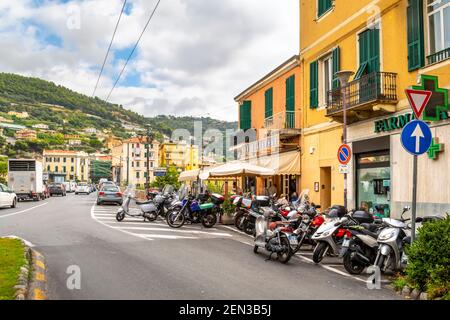A large number of scooters, motorcycles and motor bikes park outside a neighborhood bar cafe with patio in Ventimiglia, Italy, on the Italian Riviera Stock Photo