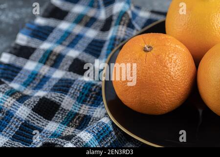 Three ripe oranges on black plate Stock Photo
