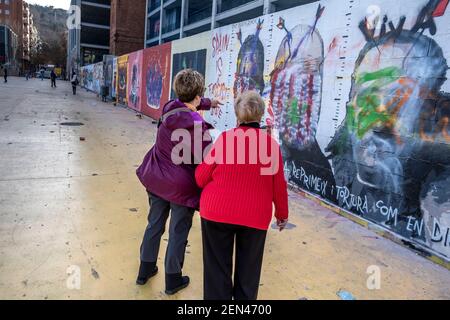 Barcelona, Spain. 25th Feb, 2021. Two women are seen commenting on the vandalized mural by graffiti artist Rock Black Block in the Plaza de Les Tres Ximeneies.Few days after being painted the murals defending the Freedom of Expression and against the imprisonment of rapper Pablo Hasel appear with important parts deleted or altered with a clear intention of altering the political content of the message, especially that of the graffiti artist Rock Black Block against the Spanish monarchy. (Photo by Paco Freire/SOPA Images/Sipa USA) Credit: Sipa USA/Alamy Live News