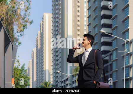Asian businessman is standing and talking with his colleague in phone on the city streets during your morning commute. Stock Photo