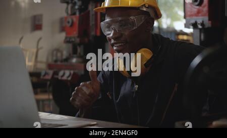 Social distance group of industrial worker, American industrial black young worker man with yellow helmet having teleconference or video conference ca Stock Photo