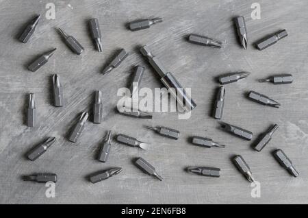 Screwdriver bits for various slots scattered on a gray concrete surface. Stock Photo
