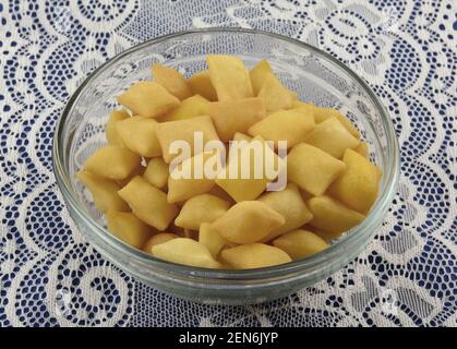 Crunchy bite size cheese bread snack in glass bowl on white lace Stock Photo