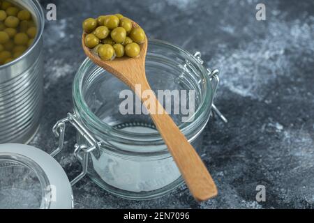 Spoon olive over empty jar on grey background Stock Photo