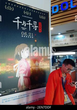 --FILE--A filmgoer waits in front of a poster of Japanese animated film 