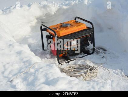 Usage of gasoline portable outdoor generator, home power generator to backup the house during blackouts, outages as a result of a winter storm. Stock Photo