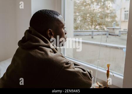 Thoughtful man looking through window at home Stock Photo