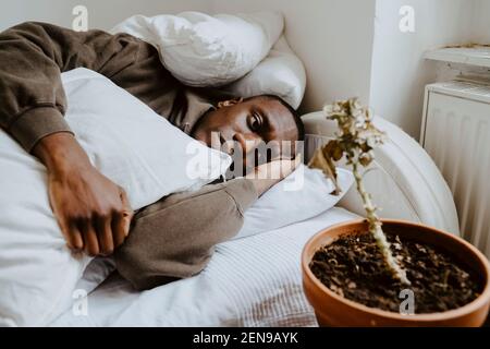 Exhausted young man resting on bed at home Stock Photo