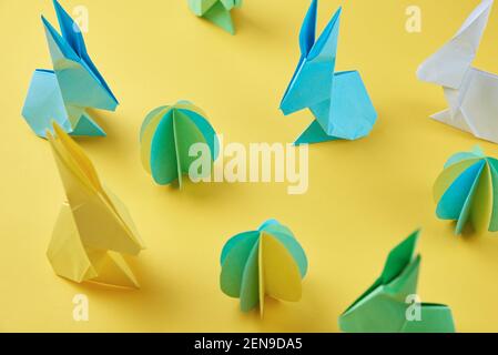 Paper origami Esater rabbits and colored eggs on yellow background. Easter celebration concept Stock Photo