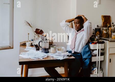 Worried businessman with hands behind head working on laptop at table Stock Photo