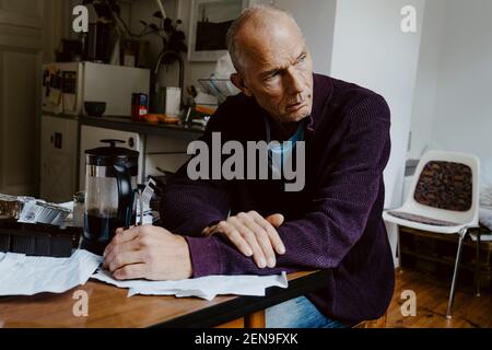 Thoughtful man looking away while sitting in living room Stock Photo