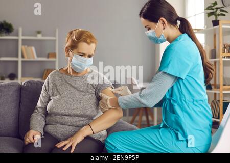 Nurse disinfects skin on senior woman's arm before giving her flu or Covid-19 vaccine Stock Photo