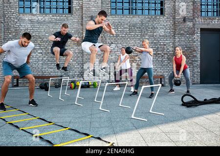 Group of people working out and jumping over hurdles, body workout Stock Photo