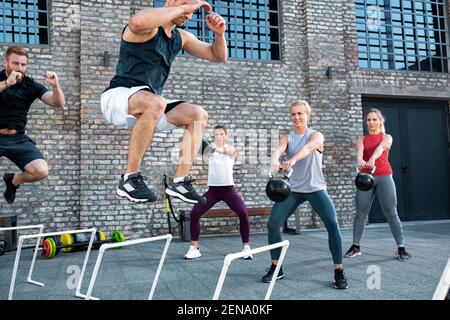 Group of people working out and jumping over hurdles, body workout Stock Photo