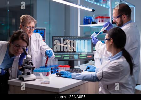 Team of scientific investigation examining resultes of DNA test in equipped lab. Biochemist scientists conducting treatment research trying to discover vaccine against covid19 virus using blood test Stock Photo