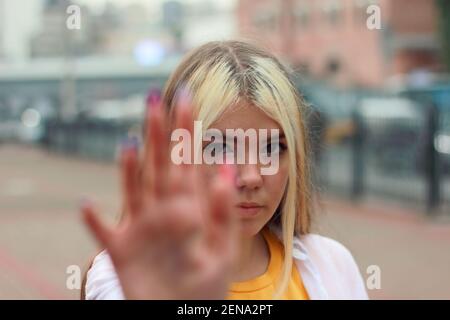 Young teenage girl with blond long hair showing stop sign with hand stopping looking at her Stock Photo