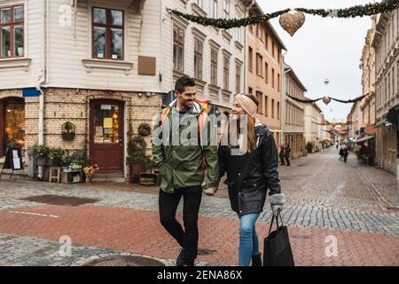 Smiling couple holding hands while walking on street in city Stock Photo