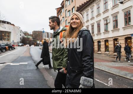 Heterosexual couple holding hands while crossing street in city Stock Photo