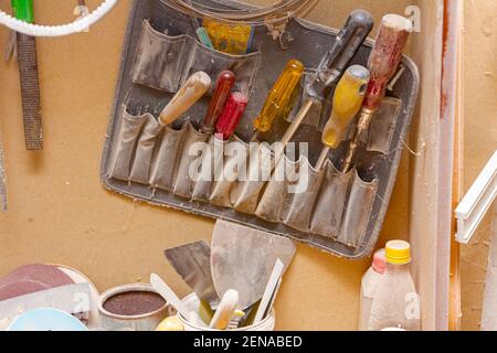 View on heap of different screwdrivers placed in a tool case and hanged on the wall in carpentry. Stock Photo