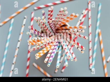 Striped and dotted paper drinking straws in a glass on grey background top view. Eco friendly and biodegradable Stock Photo