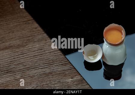 Broken chicken egg on black floor. Copy space, Selective focus. Stock Photo