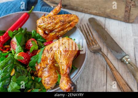 Green Salad with spicy chicken on a plate with rustic knife and fork Stock Photo