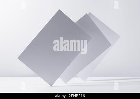 Abstract white grey minimalist background with flying papers in light with shadow as blank copy space. Stock Photo