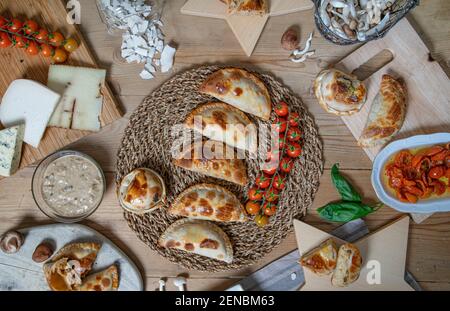 Variety of Argentine homemade empanadas and their ingredients on the wooden table. Stock Photo