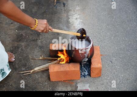 Women preparing a divine food made of rice in earthen pots and offer it to the Attukal Amma (Goddess of the Temple) during attukal pongala. Kerala Stock Photo